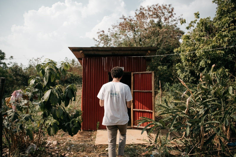 Man stands beside rural wooden shack