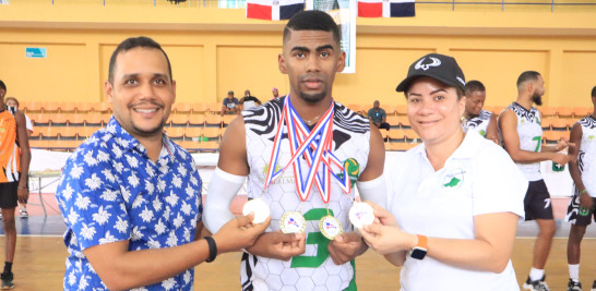 Hombre sosteniendo medallas junto a deportistas