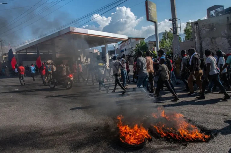 Protesters march near burning street debris