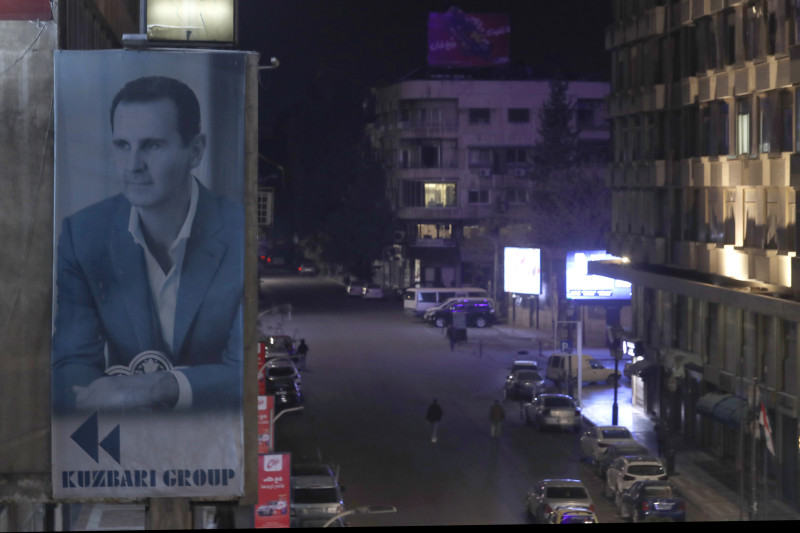 Una pancarta gigante del presidente sirio Bashar Assad cuelga en la fachada de un edificio, mientras un peatón camina por las calles vacías de Damasco, Siria, el sábado 7 de diciembre de 2024. (Foto AP/Omar Sanadiki)