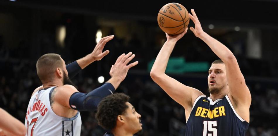 Nikola Jokic busca anotar dos puntos ante el acoso de Jordan Poole y Jonas Valanciounas en el choque que ganaaron los Wizards.