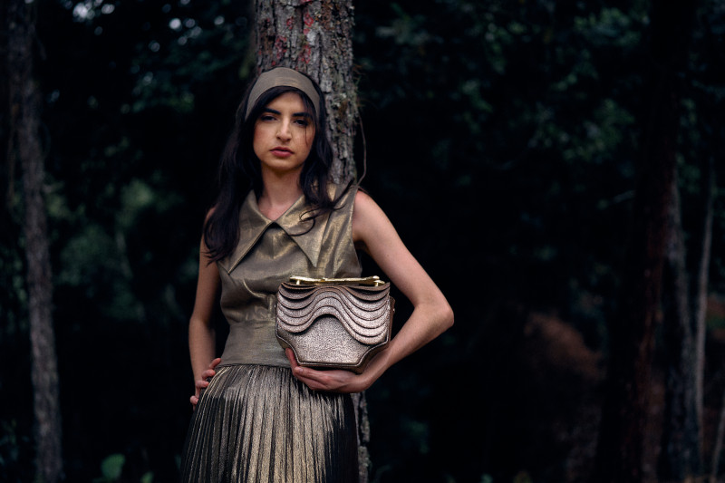 Mujer con vestido dorado y cartera