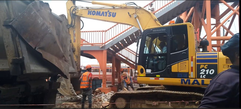 Excavadora demoliendo edificio con trabajadores