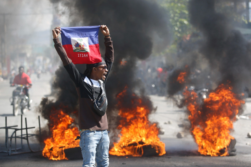 Manifestante con bandera haitiana en protesta