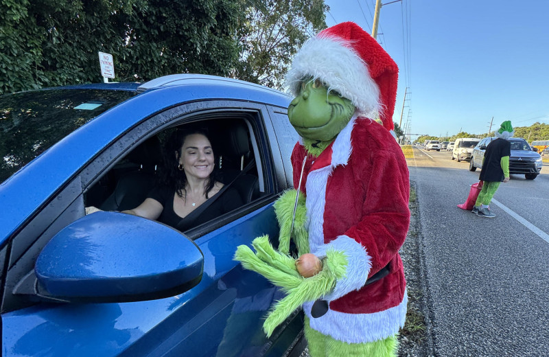 Hombre disfrazado del Grinch junto auto