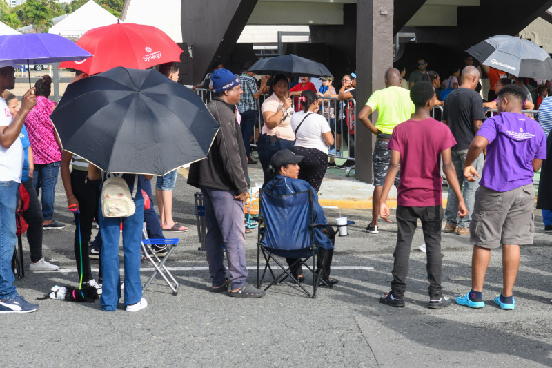 Gente espera en fila bajo lluvia