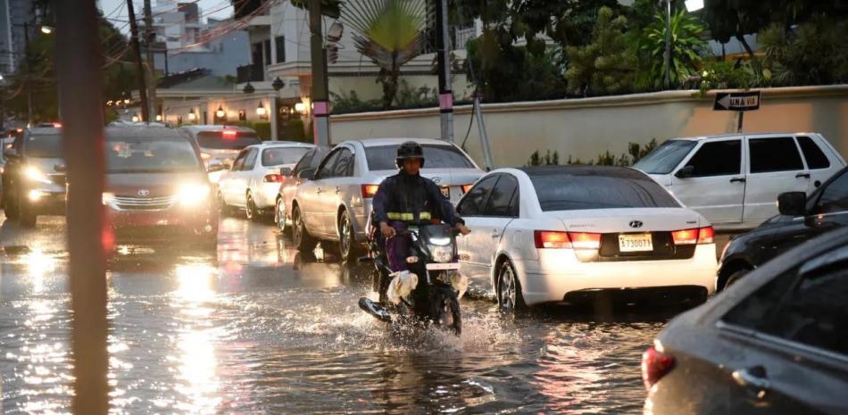 Motociclista atraviesa calle inundada en ciudad