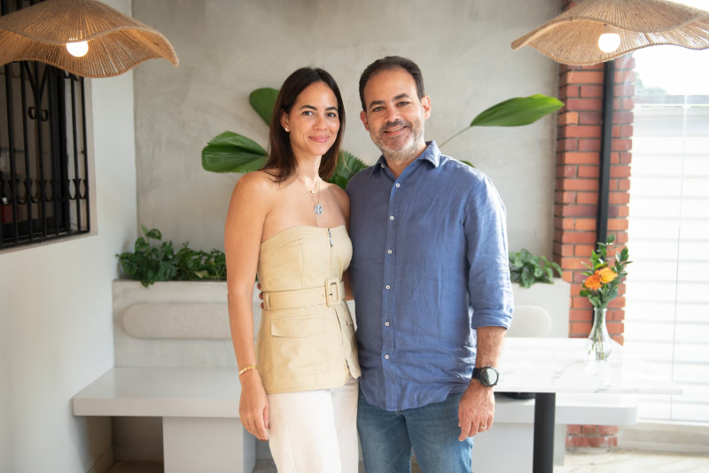 Pareja posa frente a pared gris