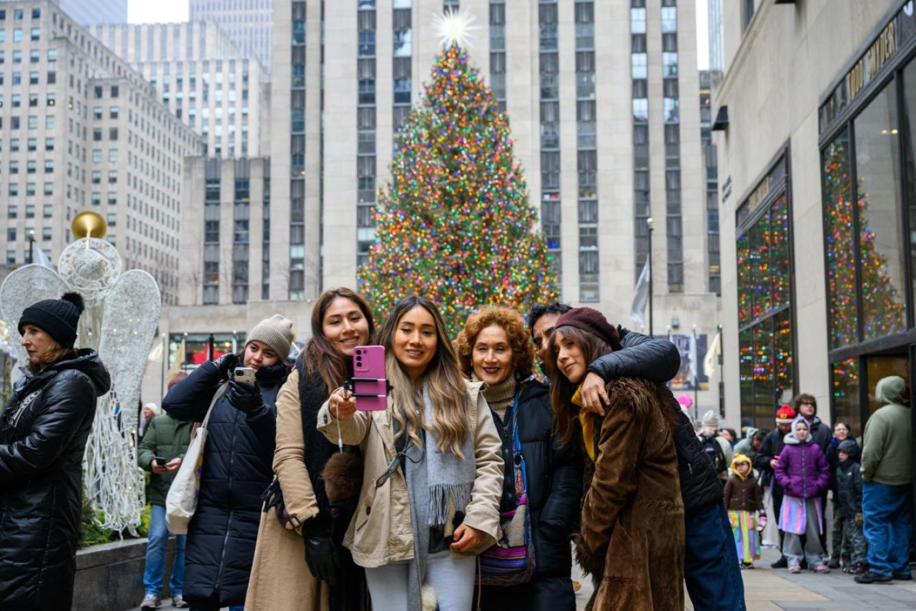 Familia tomando selfie junto árbol navideño