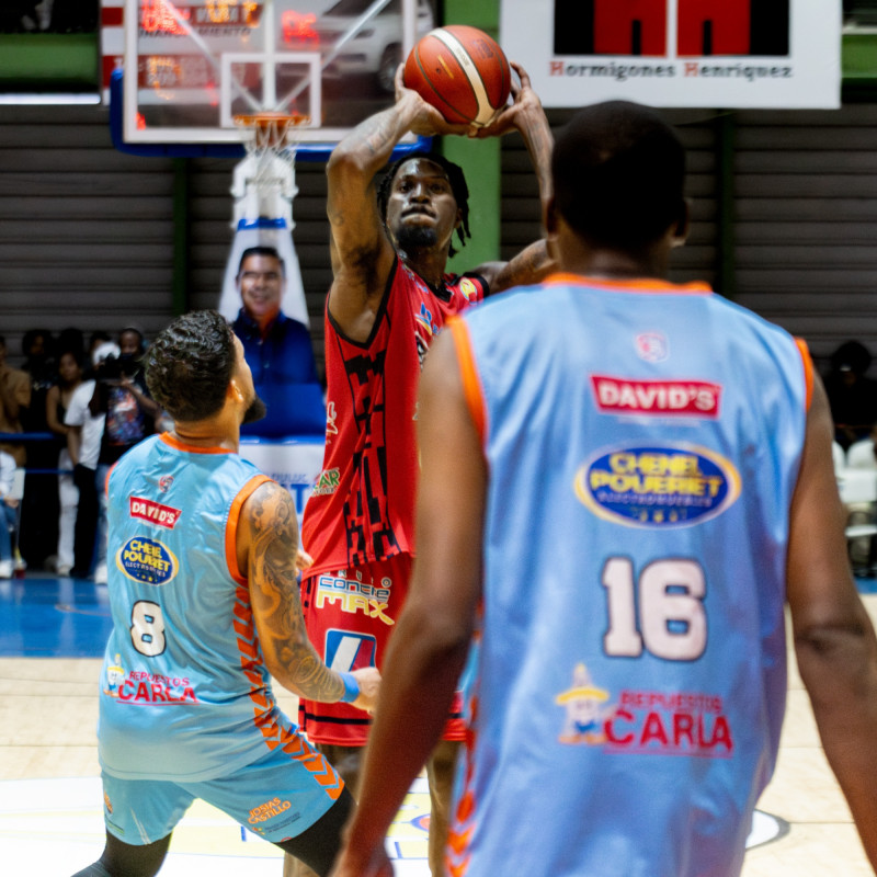 Jugador lanzando balón entre dos defensores