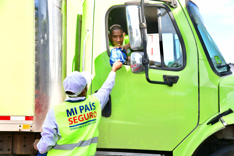 Trabajador entrega paquete desde camión verde