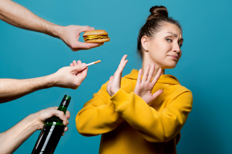 Mujer rechaza cigarro y hamburguesa