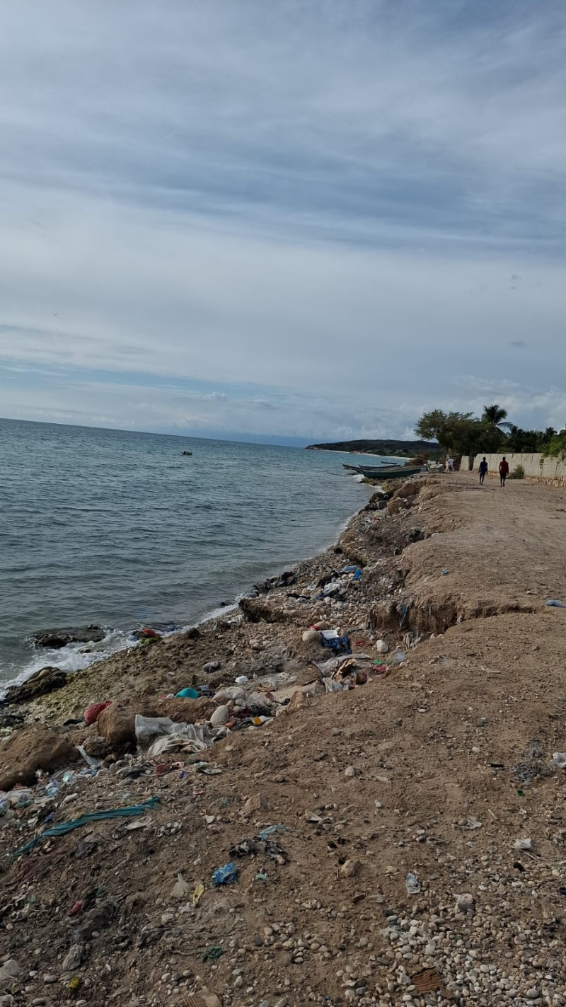 Basura en playa con personas caminando