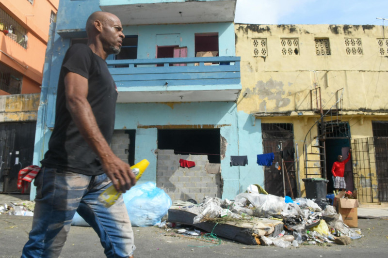 Hombre camina frente a basura acumulada