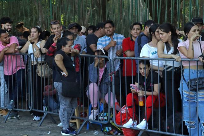 Multitud juvenil espera tras barreras metálicas