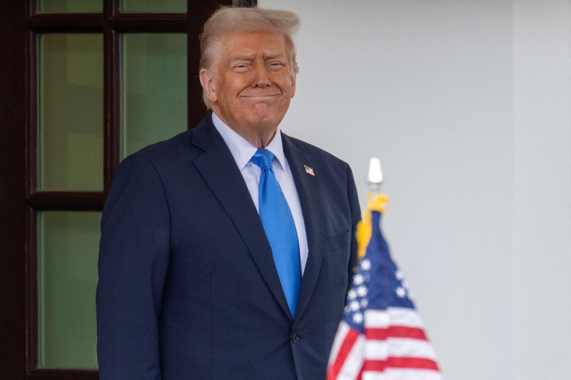 Trump sonriendo con bandera estadounidense