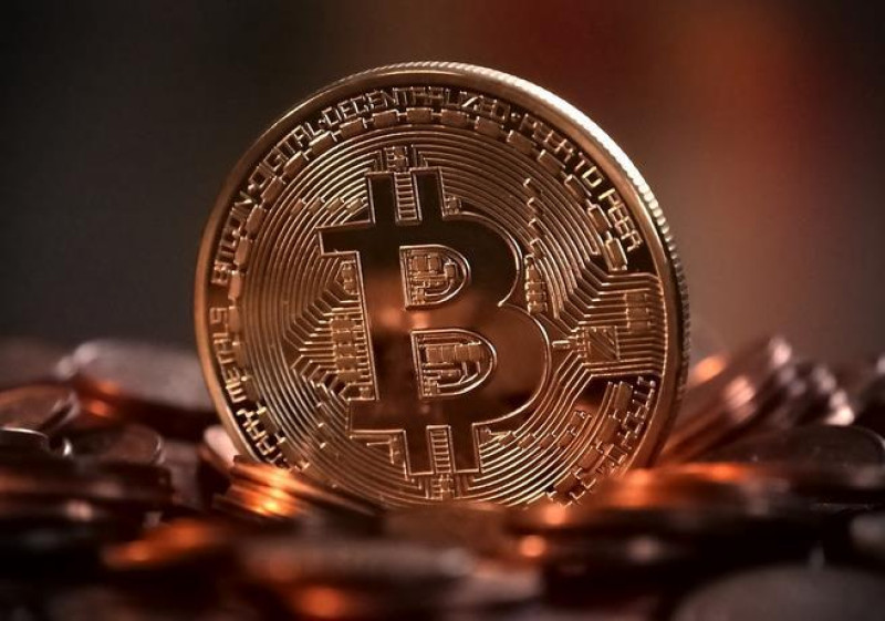 Moneda Bitcoin sobre montón de dinero