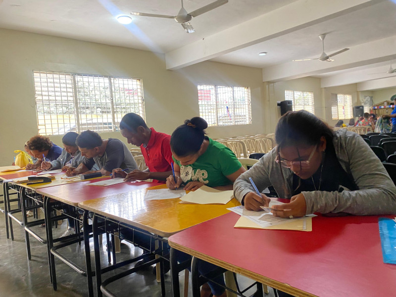 Estudiantes escribiendo en mesas largas