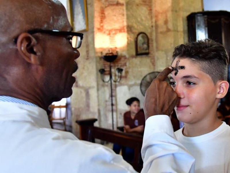 Sacerdote impone ceniza en frente