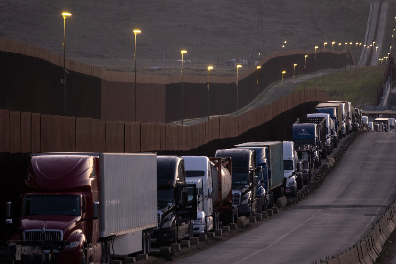 Camiones estacionados junto muro fronterizo